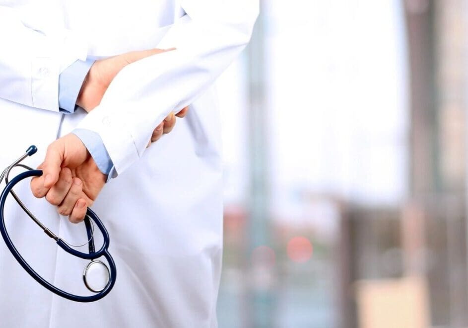 A person in white lab coat holding a pair of stethoscopes.